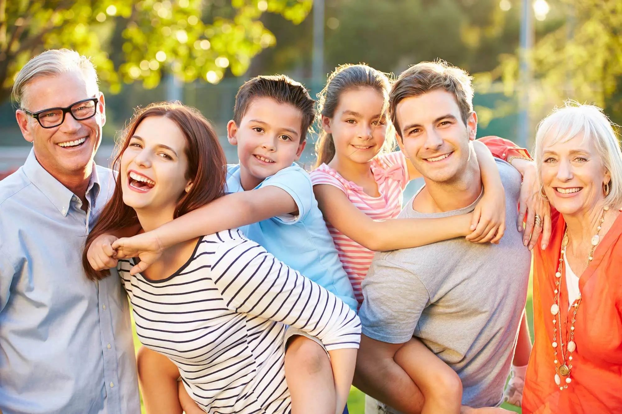3 Generationen einer Familie lächeln und posieren gemeinsam für ein Erinnerungsfoto.
