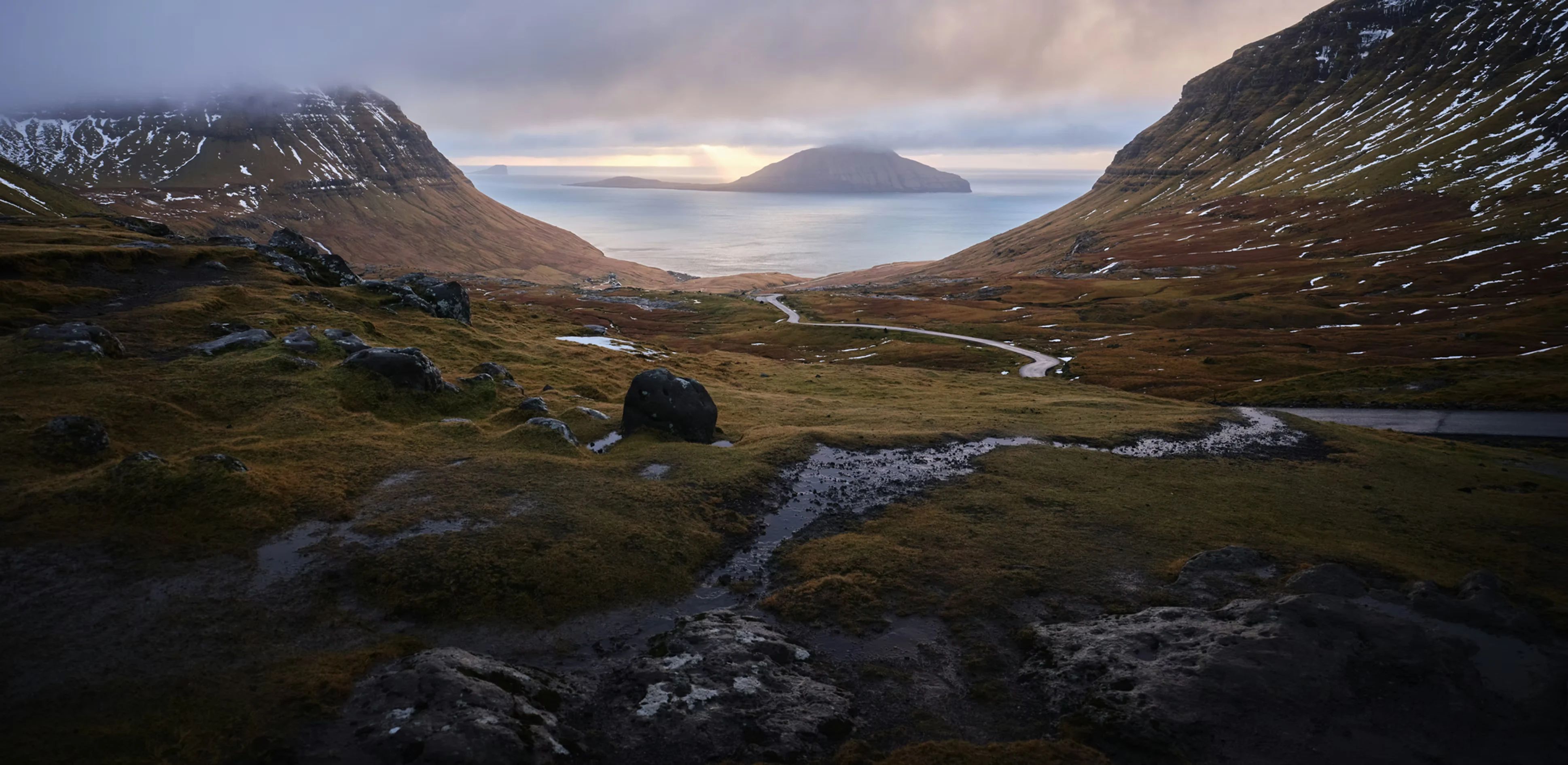 Image by Joshua Kettle. Es zeigt eine Hügellandschaft mit Meerblick.